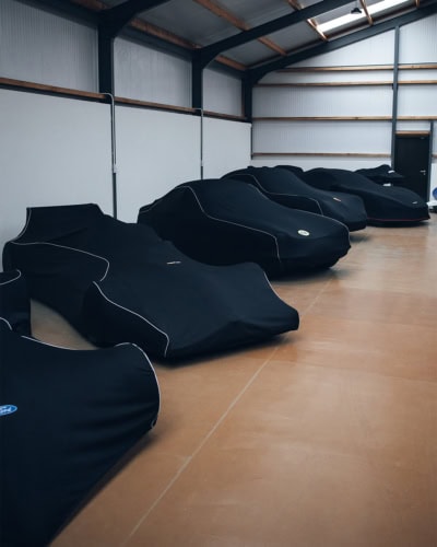 Customised black vehicle covers with premium fabric and white stitching for exceptional car cover solutions.