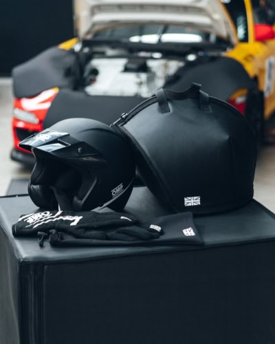 Black helmet and gear bag for racing cars, set ready for track day or race event, featuring high-quality covers and safety accessories for motorsport performance.