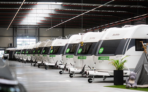 Modern camper vans with customised covers at a specialised coverings showroom in a sleek, industrial setting.