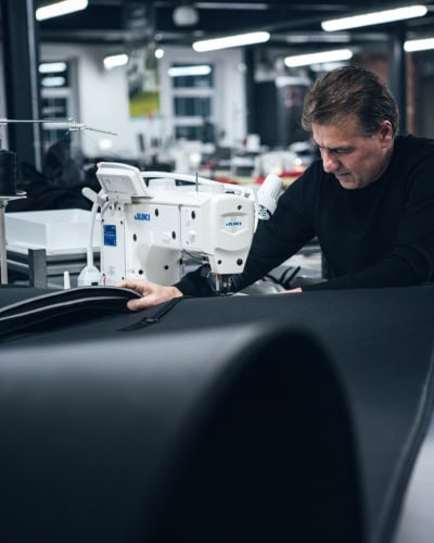 Skilled technician sewing durable protective covers with industrial sewing machine in manufacturing facility, ensuring high-quality engineered protection for defence and industrial applications.