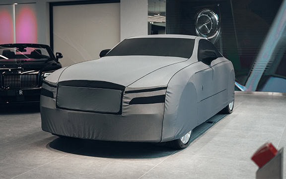 Car cover protecting a sleek vehicle at an exhibition.