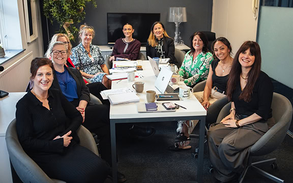 A diverse group of professionals collaborating around a table during a Knowledge Transfer Partnership meeting at Specialised Covers.