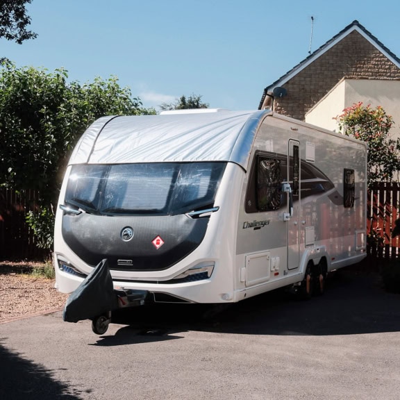 Modern caravan with a sleek design parked outdoors under a clear blue sky.