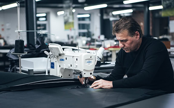 Skilled worker sewing durable industrial covers in a modern manufacturing facility for specialised covers.