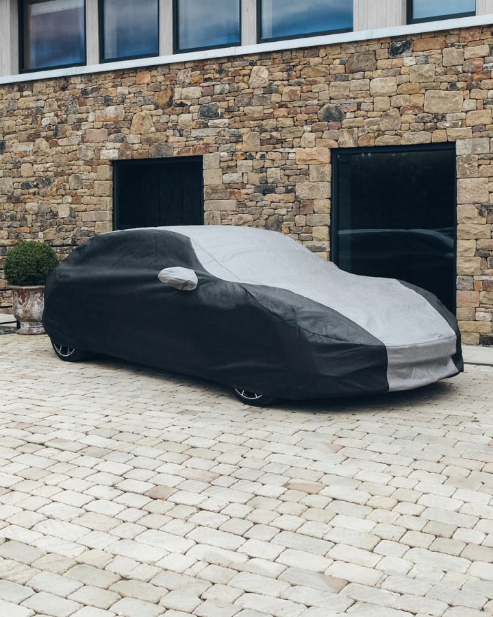 A bespoke fit outdoor car cover in black and grey on a Porsche.