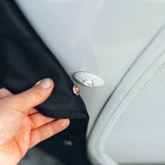 1. Custom vehicle cover being fitted to protect a white appliance or equipment, showcasing durable, tailored fabric for outdoor and indoor protection.