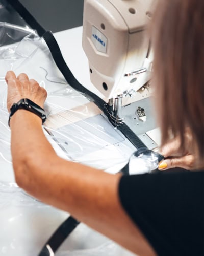 A production team member sewing some perspex material.