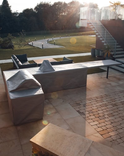A large outdoor Kitchen with a tailored fitting cover in grey.