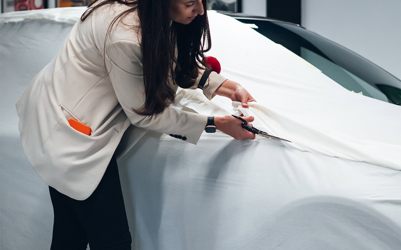 A picture of a designer cutting cloth to tailor a pattern for a BMW cover.