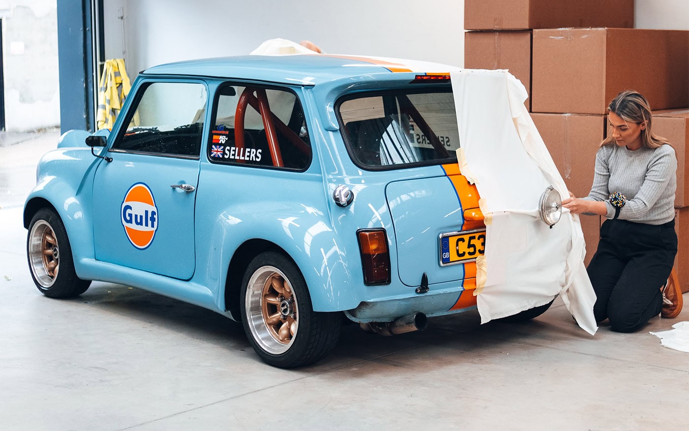 A picture of a designer pinning cloth to tailor a pattern for a car cover.