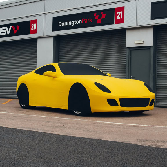 A Ferrari 599 with a yellow indoor cover on.