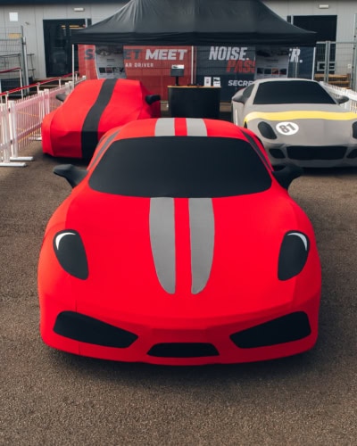 Bright red sports car with racing stripes and custom cover at Specialised Covers event, showcasing high-quality vehicle covers and car protection solutions for motorsport enthusiasts.