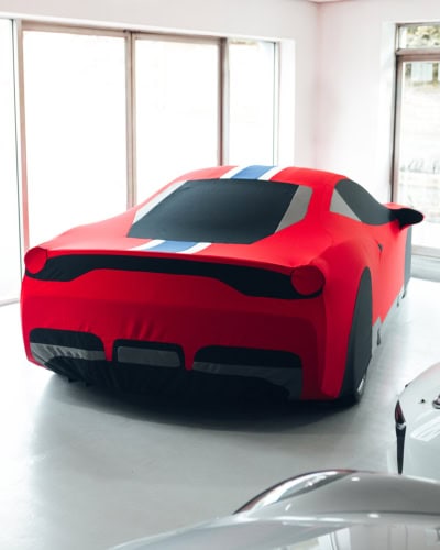 1. Custom car cover designed for showroom display, featuring a race-inspired design in red, black, blue, and grey for full vehicle protection.