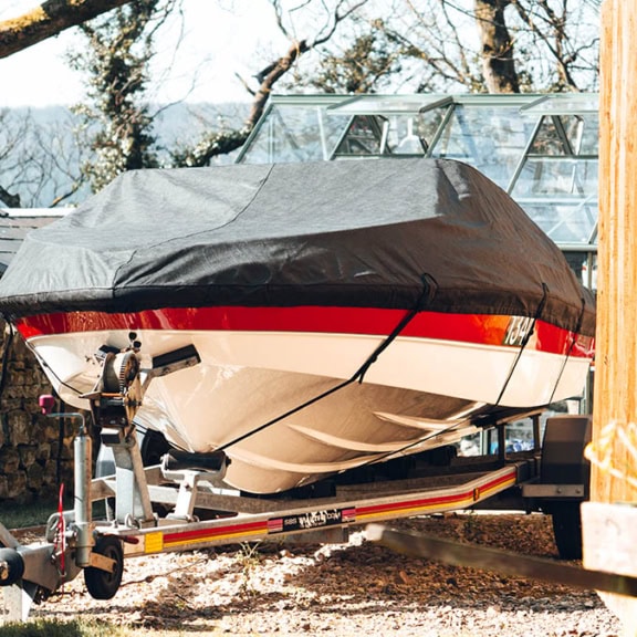 Boat cover protecting a speedboat on trailer, perfect for outdoor marine storage, custom fitted, waterproof, UV-resistant, and designed for secure outdoor covering.