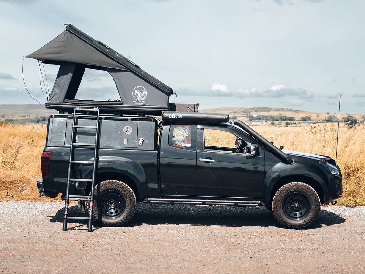 High-quality black vehicle fitted with a Nomad roof tent, perfect for outdoor adventures. The tent is comfortable, weather-resistant, and easy to setup, designed for explorers seeking reliable vehicle covers and camping gear for overland trips.