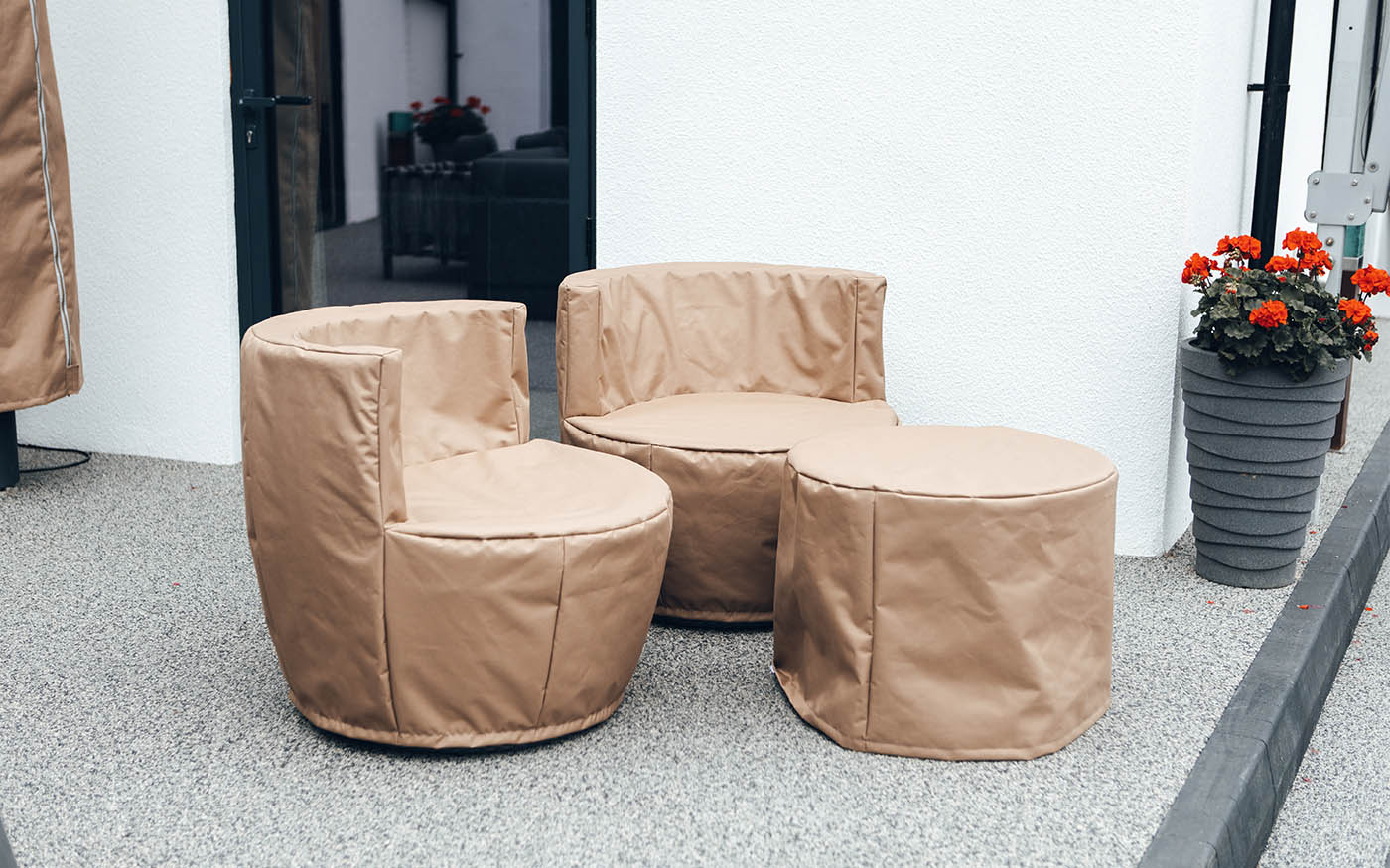 Soft beige outdoor furniture covers protecting garden chairs and ottoman from weather damage. Perfect for maintaining the look of patio furniture with custom-fit covers.