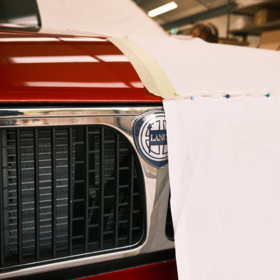 High-quality custom car cover being fitted on a vintage car in workshop, specialised covers, protect your vehicle from dust, scratches, rain, and sun damage with durable, weather-resistant car covers.