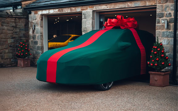Custom car cover with festive red and green design, styled as a gift wrap for protection and decoration during holidays.