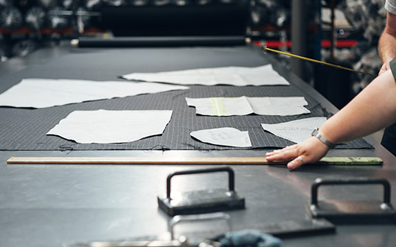 Person measuring fabric samples for custom vehicle covers on a worktable, ensuring quality and durability for tailored outdoor protection.