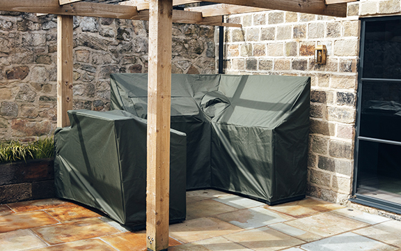 Custom outdoor furniture covers protecting a sofa and table set under a wooden pergola against weather elements.