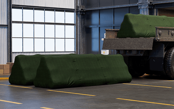 Heavy-duty green protective covers safeguarding industrial machinery and equipment in a warehouse setting.