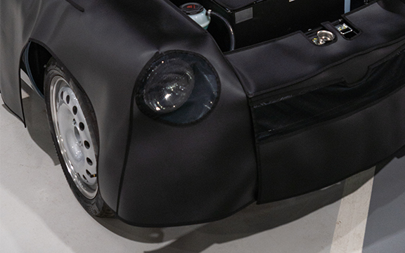 Close-up of a vehicle with a protective body cover, highlighting the sleek black material designed for vehicle protection and durability.