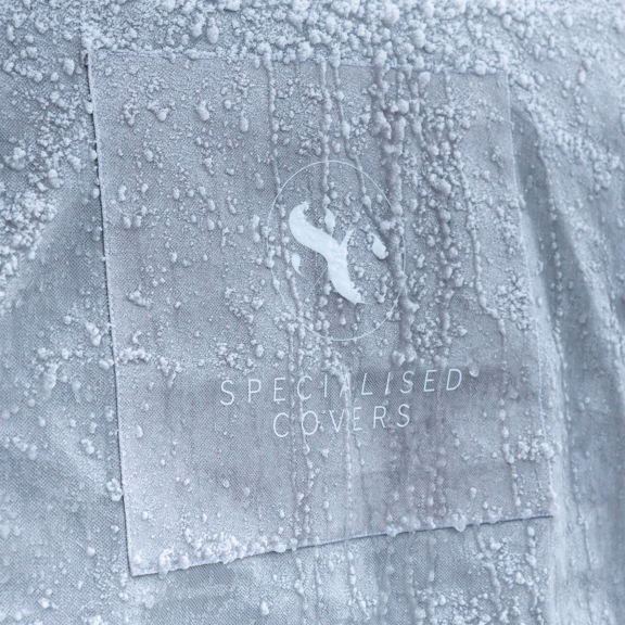 Full caravan storage cover in snow with water droplets, designed to protect caravans from weather damage.