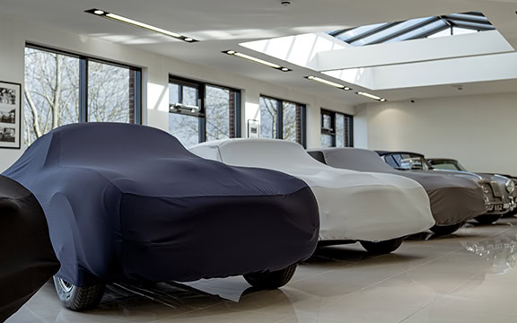 Collection of tailored car covers in a showroom, protecting vintage and classic cars with high-quality materials for optimal preservation.